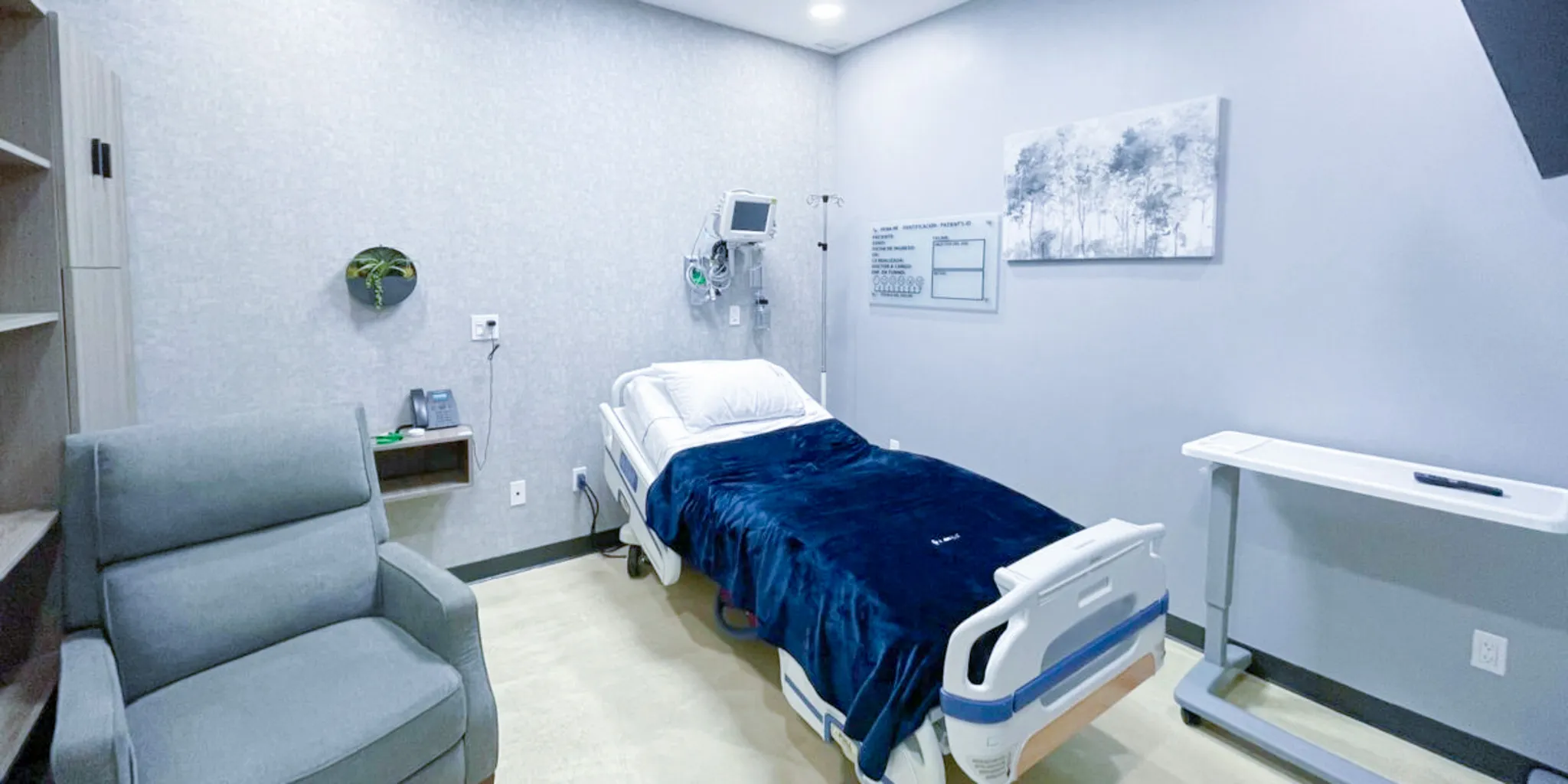 Patient room with an adjustable hospital bed, a vital-signs monitor and an armchair